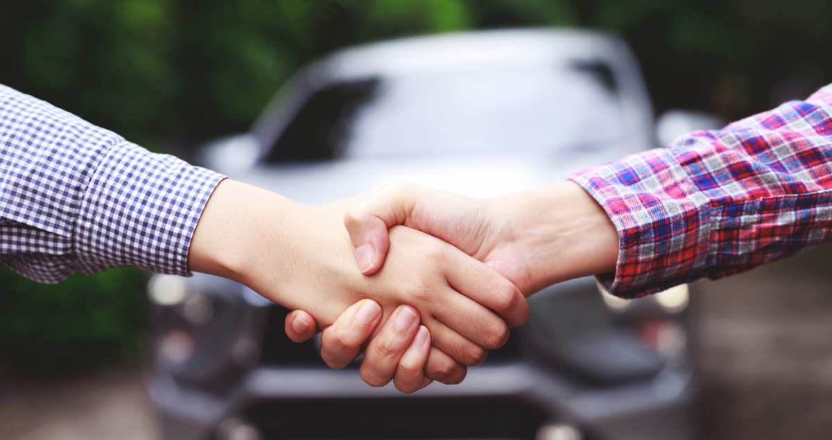 People shaking hands after getting new tags on their vehicle.